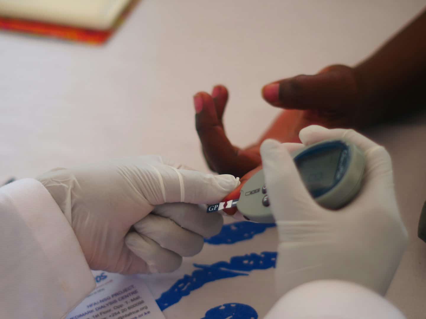 Healthcare professional using a glucose meter to test a patient's finger.
