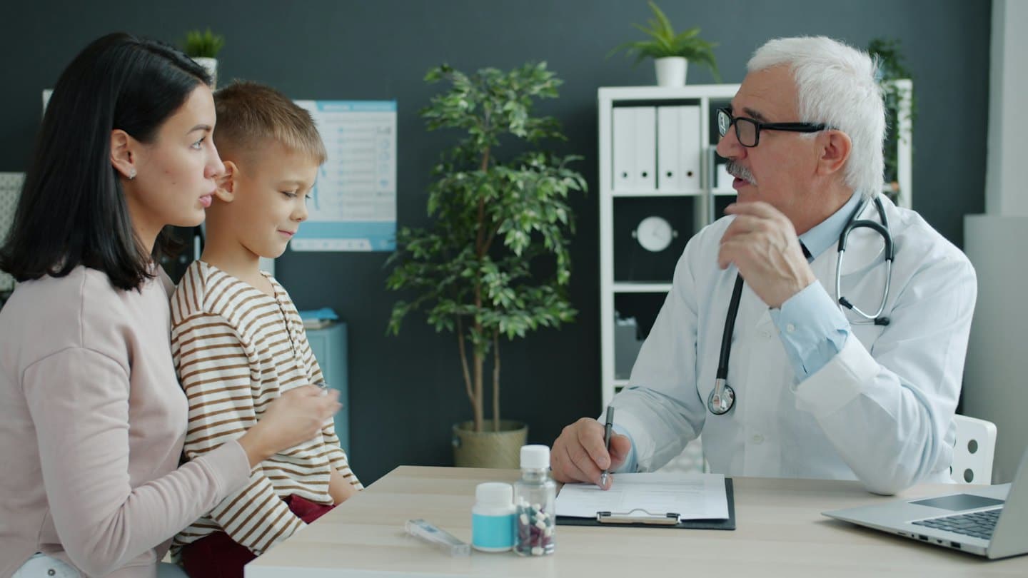 Doctor consults with mother and child in office.