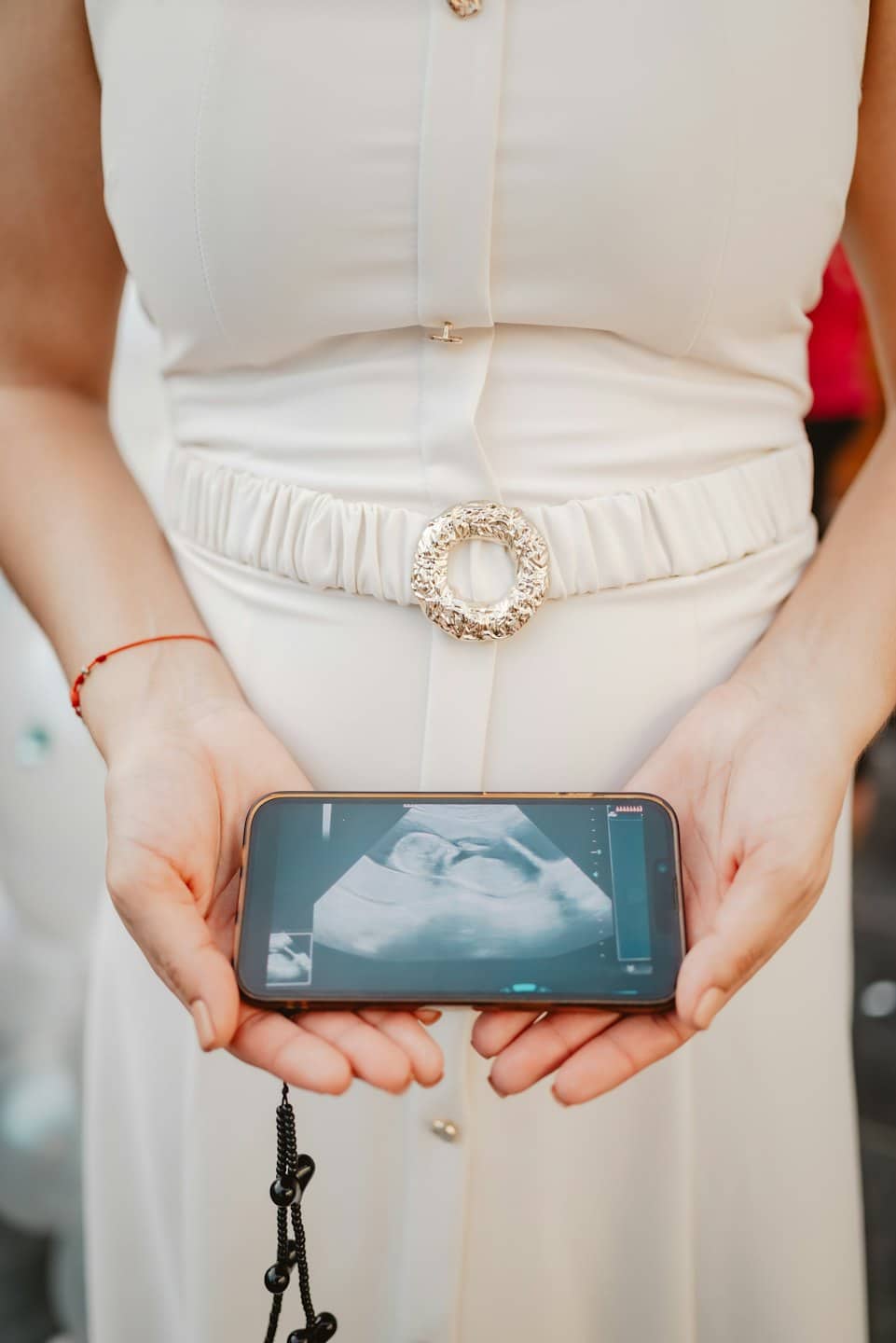 A person holds a smartphone displaying a prenatal ultrasound image.